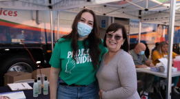 nurse in mask standing next to member of the community 