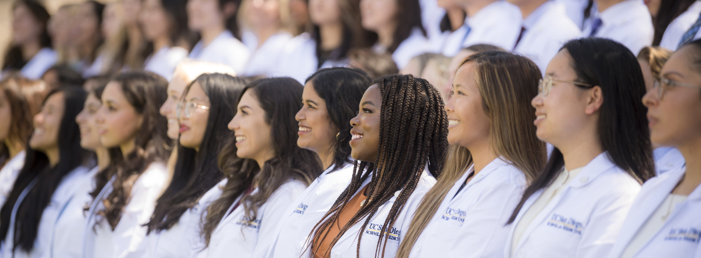 medical students in white lab coats at commencement