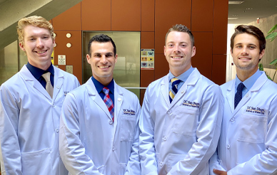 Four male medical students in white coats