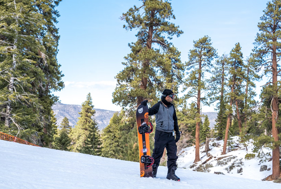 man standing in snow holding a snowboard