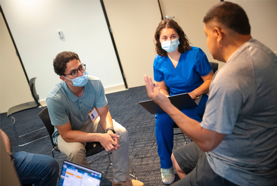 Student-Run Free Clinic male patient speaking with a group of medical students and physicians