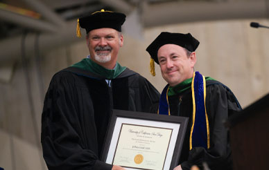 Sean Evans, M.D. presenting teaching award certificate to Jeff Gold, M.D. at School of Medicine Commencement