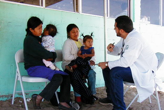 Man in white coat speaking with two mothers with small children on their laps