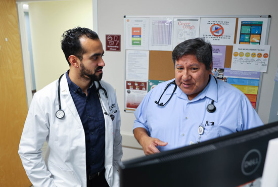 Native American physician and medical student  talking while looking at computer monitor