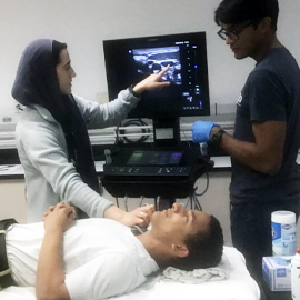 female student showing male student how to use the ultrasound machine