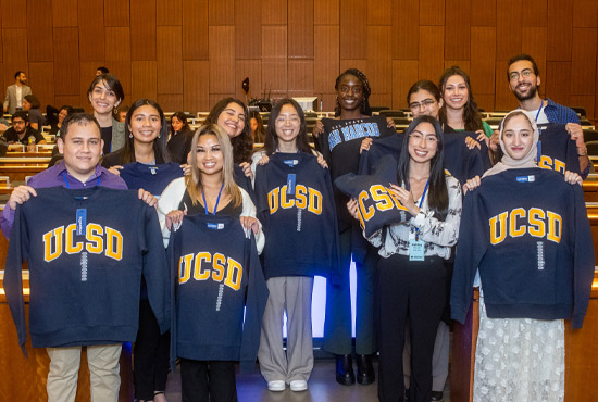 group of student holding up college sweatshirts