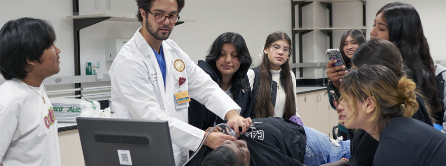 2 of 6, male medical student showing high school students how ultrasound images on screen