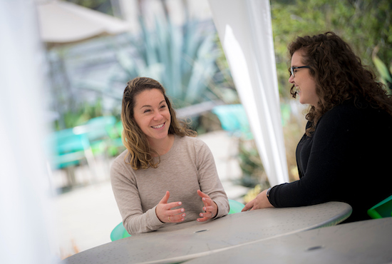 two women sitting at a table smiling