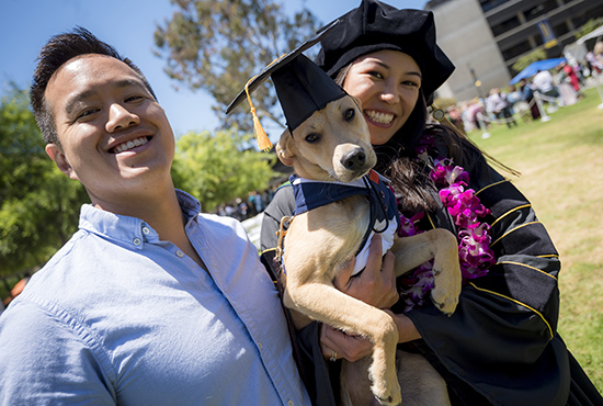 School of Medicine graduate poses with a dog and friend.