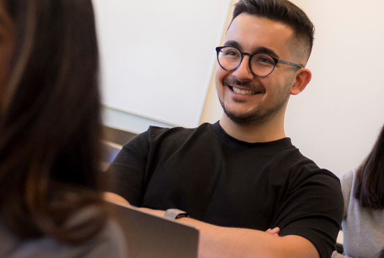 male student sitting at  laptop smiling