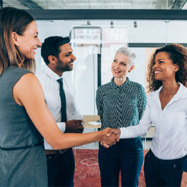 four people in a circle, two shaking hands and smiling