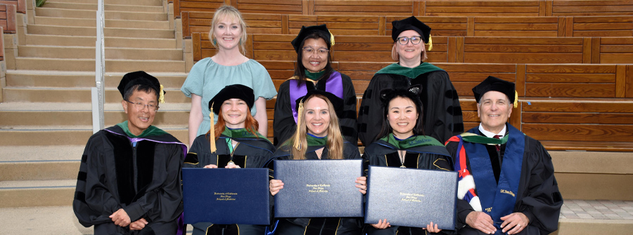 5 of 11, Commencement group photo of students and faculty members. Students are holding their diploma covers.