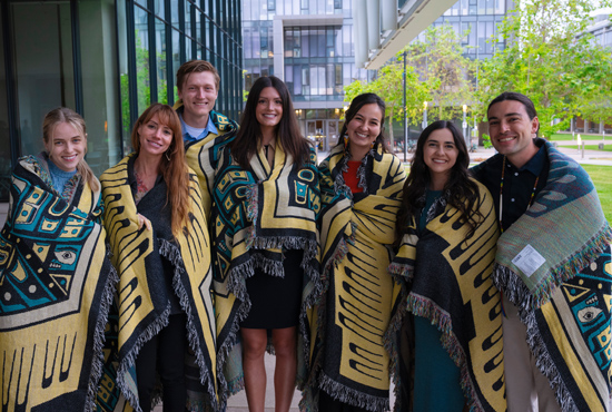 Group of 7 Native  American student smiling wrapped in blankets of knowledge