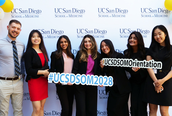 Medical students holding orientation signs in front of backdrop