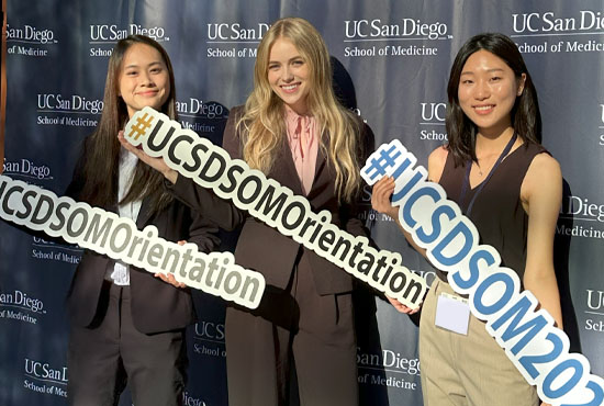 Medical students holding orientation signs in front of backdrop
