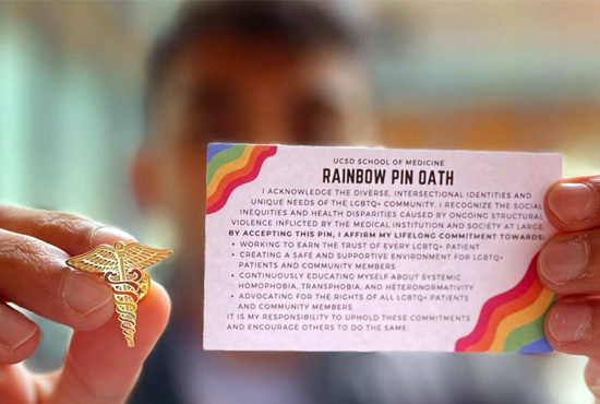 student holding rainbow pin and card with the with the rainbow pin oath printed on it