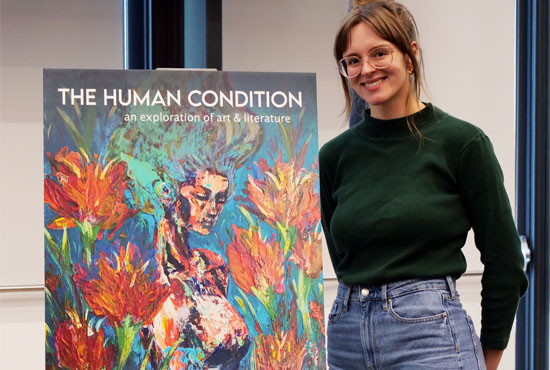 Student standing next to large poster of the cover of The Human Condition magazine