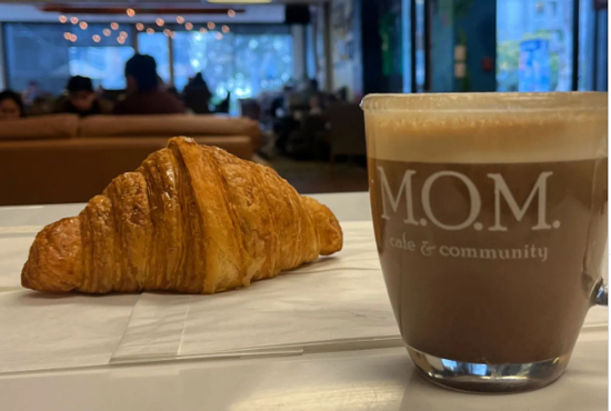 Clear coffee mug filled next to a croissant