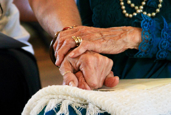 Elderly woman holding hands with younger hands
