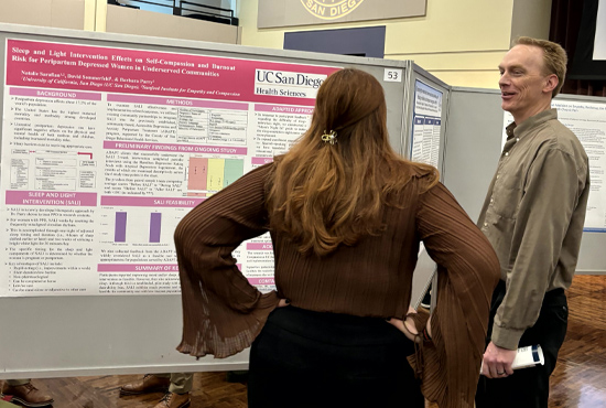 female student and professor talking about research poster facing away from camera