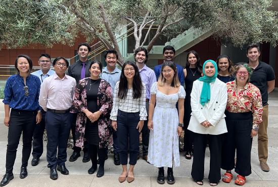 Group of students and mentors standing together outside under a tree